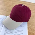 Dettaglio del berretto bicolore con corona bordeaux e visiera beige su scrivania in legno - Regolabile / Rosso Vino e Tesa Beige