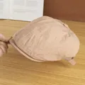 Dettaglio di un berretto beige leggero con cuciture a contrasto su un piano in legno - Regolabile / Rosa