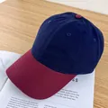 Detail of two-tone cotton baseball cap with navy crown and burgundy brim on a table - Adjustable / Navy Blue and Wine Red Brim