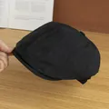 Dettaglio di un berretto newsboy nero leggero che mostra la trama traspirante sul legno - Regolabile / Nero
