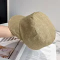 Detail of khaki newsboy cap showing linen texture held over a magazine background - Adjustable / Khaki