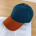 Detail shot of a contrast baseball cap in dark green and orange on a wooden surface - Adjustable / Dark Green and Orange Brim