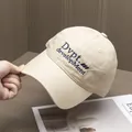 Détail de la broderie bleue sur la casquette en coton beige avec couture texturée - Réglable / Poche zippée