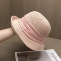Détail du chapeau de paille rose avec ruban plissé élégant sur fond de bois naturel - Rose
