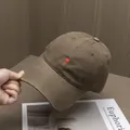 Dettaglio del ricamo a cuore e lettera C su un cappellino di cotone marrone - Regolabile / caffè