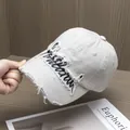 Dettaglio del cappellino ricamato con bordi sfilacciati, effetto usurato e cotone lavato - Regolabile / Bianco Grigiastro