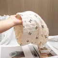 Detailed view of cream-white breathable cotton maternity hat with black bow patterns - M (56-58cm) / Beige