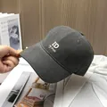 Detail of dark grey baseball cap featuring white ID letter embroidery and twill texture - Dark Gray