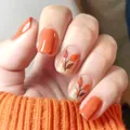 Glossy orange press-on nails with autumn maple leaf patterns and knit sweater background - Orange Maple Leaf Pattern (YS727)