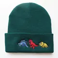 Detail der drei bunten Cartoon-Dinosaurier-Stickereien auf einer dunkelgrünen Strickmütze - Verstellbar / Dunkelgrün