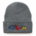 Detailaufnahme einer grauen Strickmütze mit drei bunten Cartoon-Dinosaurier-Stickereien - Verstellbar / Melange Grau