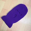 Detalle de un pasamontañas de punto morado con 3 agujeros sobre una superficie de madera - Lila