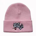 Dettaglio di un berretto in maglia rosa con ricamo di drago dettagliato sul risvolto - Taglia unica / Rosa