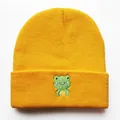 Nahaufnahme der grünen Frosch-Stickerei auf einer leuchtend gelben Strickmütze für Winter - Verstellbar / Gelb