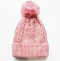 Nahaufnahme der rosa Zopfmuster-Mütze mit flauschigem Bommel und breitem Rippsaum - Verstellbar / Rosa