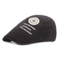 Détail d'un béret noir en coton avec texte artistique blanc et écusson de mode latéral - Réglable / Noir
