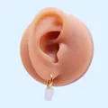 Dettaglio dell'orecchino a cerchio dorato con pendente bianco traslucido indossato - Bianco Latte (Oro)