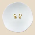 Detailansicht goldener Schmetterlings-Ohrhänger mit Zirkonia auf einer Keramikschale - Pave Schmetterling Stil (#16)