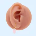 Dettaglio dell'orecchino pendente rosa traslucido con cerchio dorato su modello - Zircone rosa (Oro)