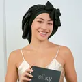 Détail du bonnet de nuit en soie noire avec nœud et emballage tenu par le modèle - Taille unique / Satin Noir (avec boîte cadeau)