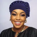 Dettaglio del turbante plissettato viola scuro con treccia e perle decorative - Blu navy