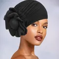 Detail view of the side-mounted large fabric flower on the pleated black turban cap - One Size / Black