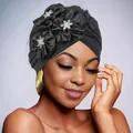 Detail of black turban cap with 3D satin flowers, rhinestones and mesh veil on model - Black