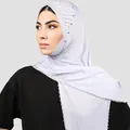Details des hellvioletten Hijabs mit eleganten weißen Perlen und funkelnden Strasssteinen - Weiß