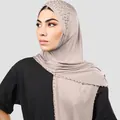 Detalle de un elegante hiyab color topo con adornos de perlas y pedrería brillante - Gris claro