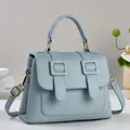 Detailed macro shot of light blue lychee pattern leather handbag with strap and handle - Blue