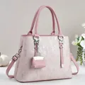 Close-up of pink handbag with metallic grain finish, silver hardware, and mini bag charm - Pink