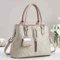 Detail van beige shopper met textuurmateriaal, metalen ringen en een kwastje - Abrikoos