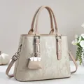 Detalle de bolso color champán con herrajes plateados y colgante de mini bolso a juego - Albaricoque