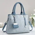 Detailed view of grey blue leather handbag with silver chain and mini charm bag accessory - Blue