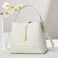 Minimalist beige pebble leather bucket bag with top handle and gold clasp detail - Pure White