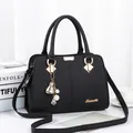 Elegant black lychee grain PU leather tote bag with gold logo and decorative charms - Black