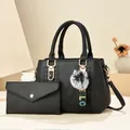 Schwarze Tragetasche aus strukturiertem Leder mit V-Nähten und flauschigem Bommel-Anhänger - Schwarzes Taschen-Set