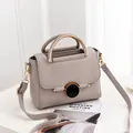 Grey pebbled leather handbag with metallic top handle and elegant round buckle design - Gray