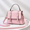 Close-up of pink crossbody bag with gold buckle hardware and elegant vertical straps - Pink