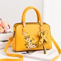 Yellow leather handbag for women featuring floral embroidery and a butterfly charm - Turmeric