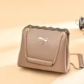 Khaki crossbody bag with golden bow hardware and wavy edge detail on metal chain - Khaki