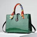 Dark green crocodile pattern handbag with gold clasp and decorative silk scarf accents - Green