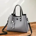 Grey PU leather handbag with black handles and silver heart charms on a wooden table - Gray