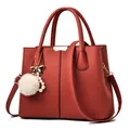 Dark red lychee pattern handbag with white plush ball charm and gold trim accents - Red