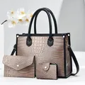 Detailed close-up of brown crocodile embossed tote bag set with golden rivets and black trim - Khaki
