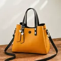 Ginger yellow PU leather handbag with black straps and heart charm in a variant view - Earthy Yellow