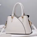 Dettaglio della borsa in pelle verniciata bianca con finiture dorate e cuciture curve - Bianco
