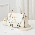 Elegant white crossbody bag with floral embroidery and pearl metallic lock detail - White