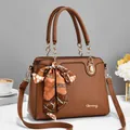 Detail of caramel lychee grain handbag with metal logo and decorative silk scarf - 29*12*21cm / Earthy Yellow