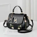 Black leather handbag with white flower embroidery and pearl buckle strap detail - Black